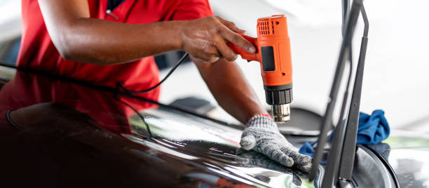 man installing window tinting on car.