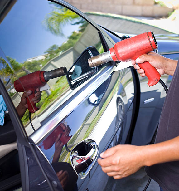 man installing window tinting on car.
